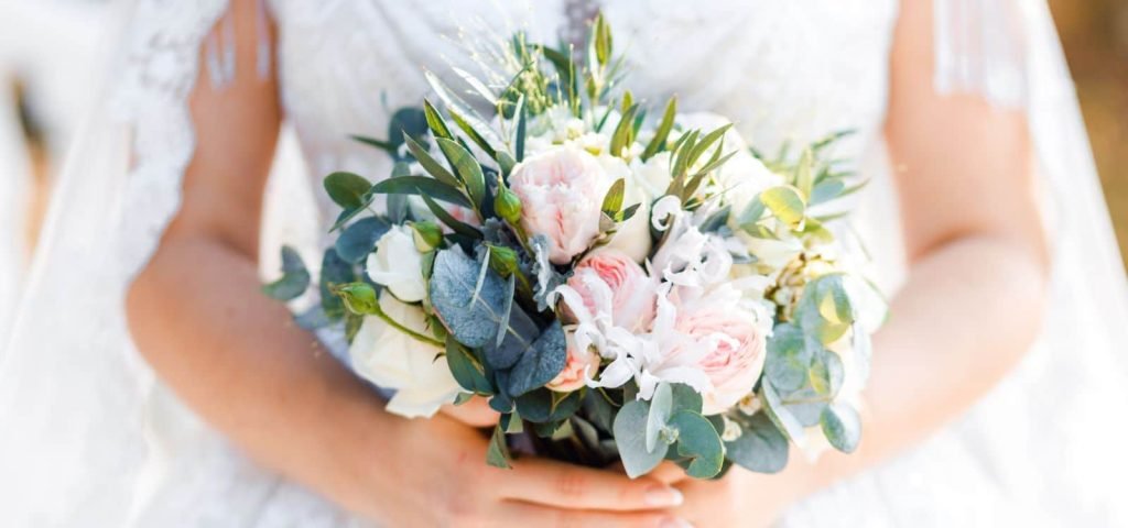 Braut hält einen Brautstrauß aus Rosen und Eukalyptus